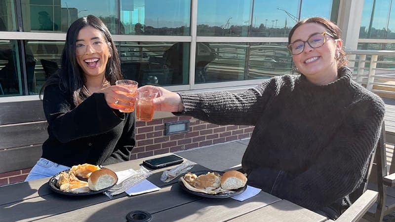 Two employees eating lunch and cheering with each other