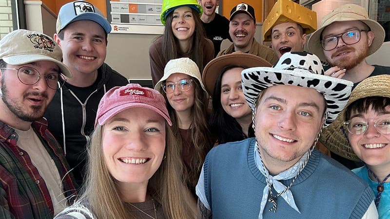 A group of employees wearing lots of different and quirky hats