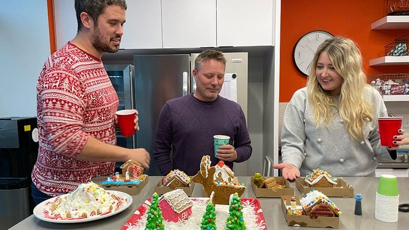 Three Omoaha employees celebrating their holidays with gingerbread houses