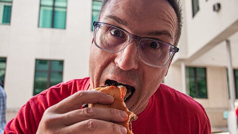An employee eating a hamburger at a tailgate party