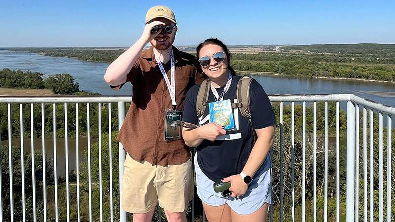 Two employees standing on an overlook above a river valley