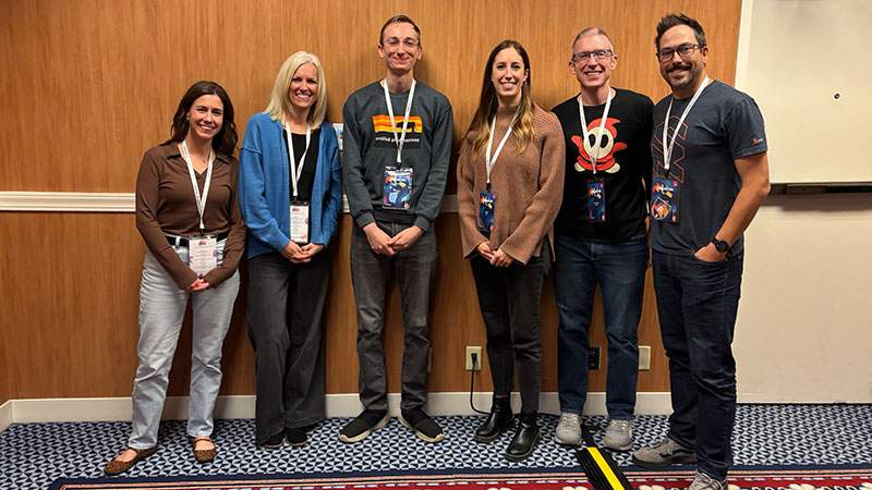 Six employees standing together with event badges