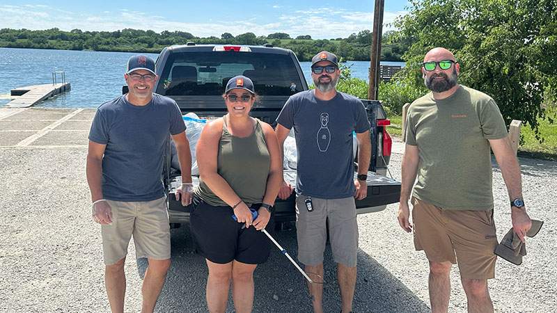 Four employees standing by a pickup truck near a lake dock