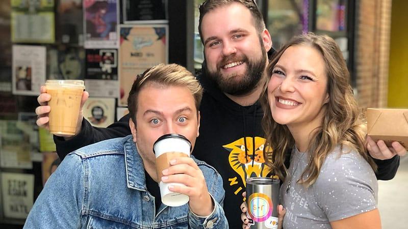 A group of employees posing for the camera with coffee in hand