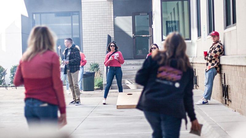 People playing bags at a tailgate party