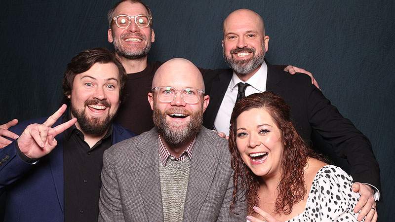 Five employees smiling together in a group portrait at an event