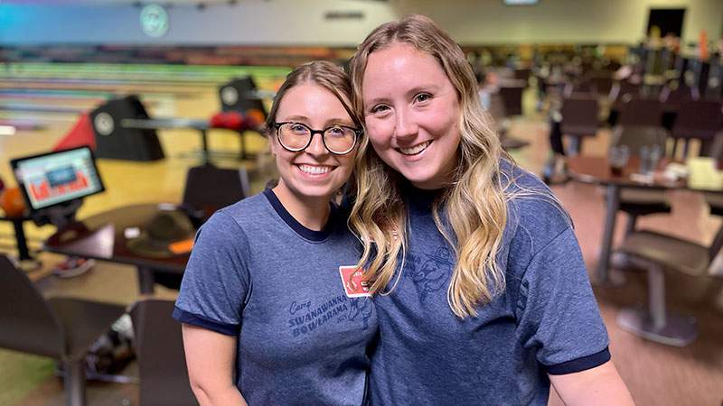 Two employees posing together at a bowling alley
