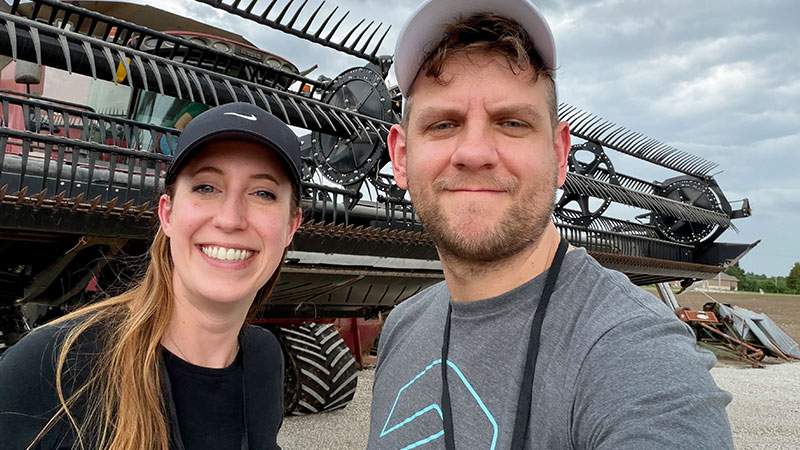 Two employees taking a selfie in front of a combine header