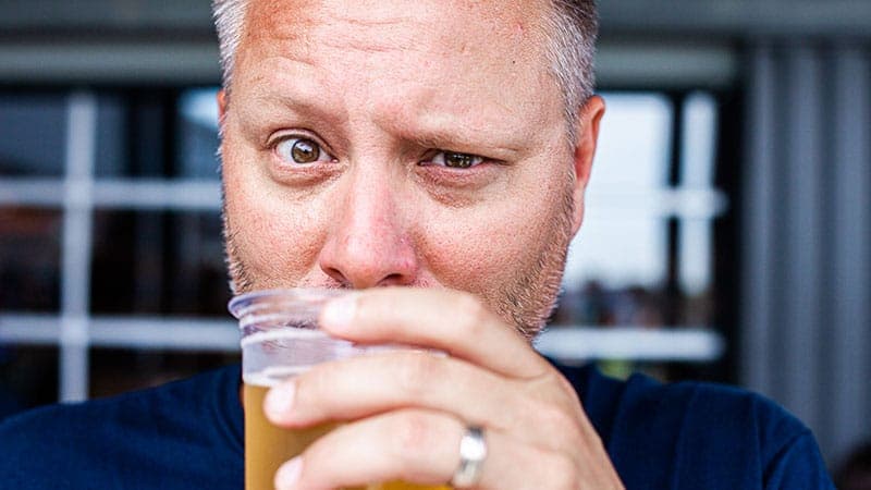 Employee drinking a beer with a confused look on his face