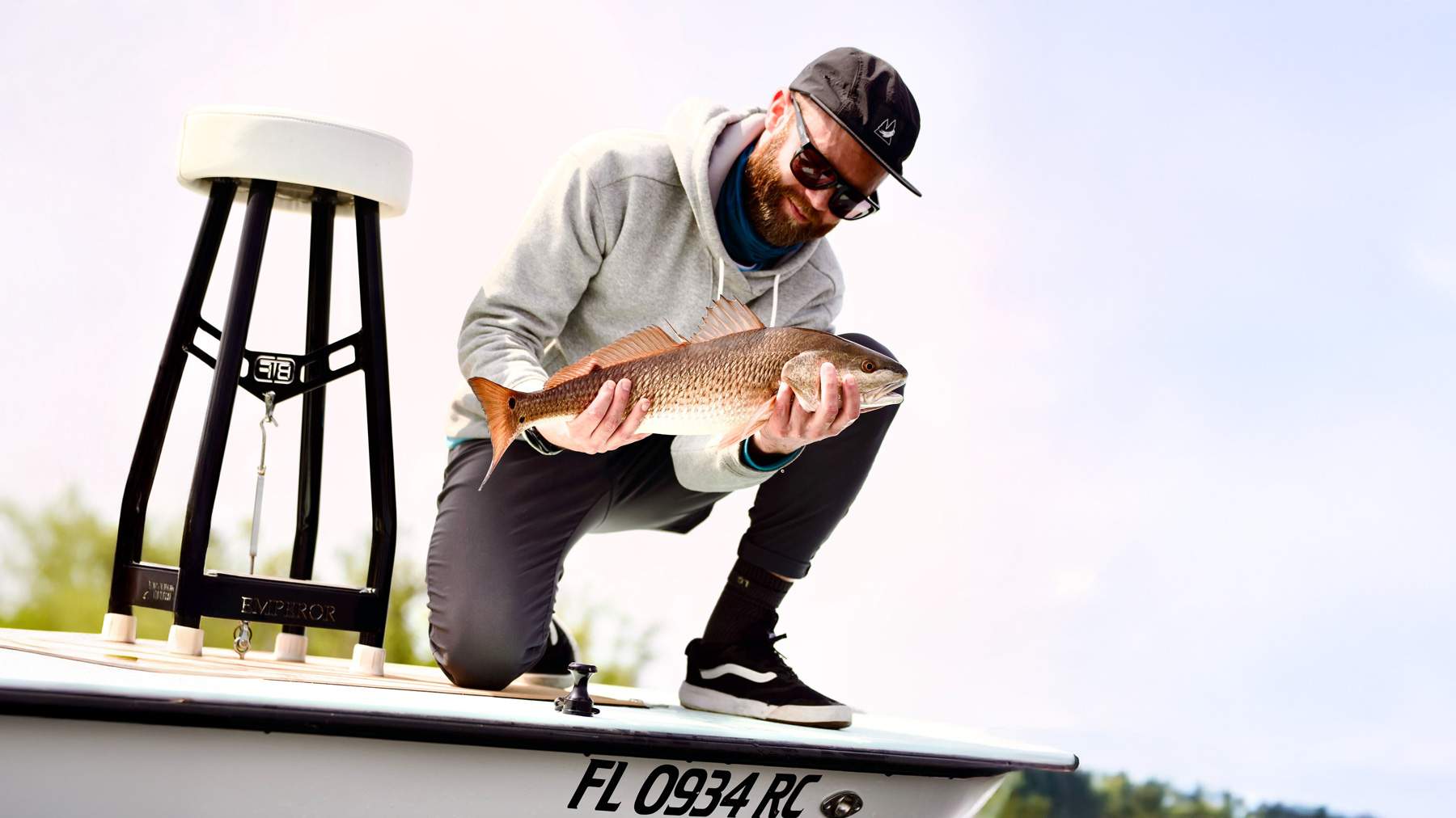 Man on a boat holding a freshly caught fish.