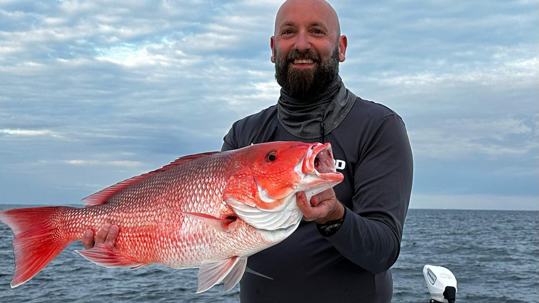 Man on a boat holding a freshly caught fish.