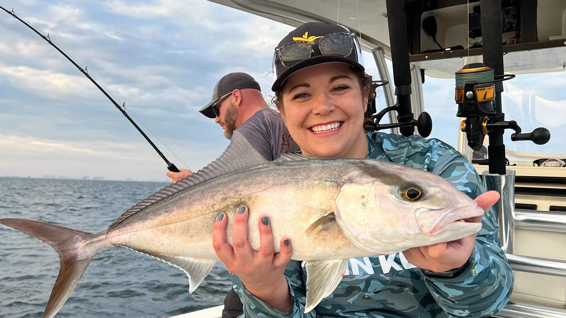 Woman sitting on a boat holding a freshly caught fish.