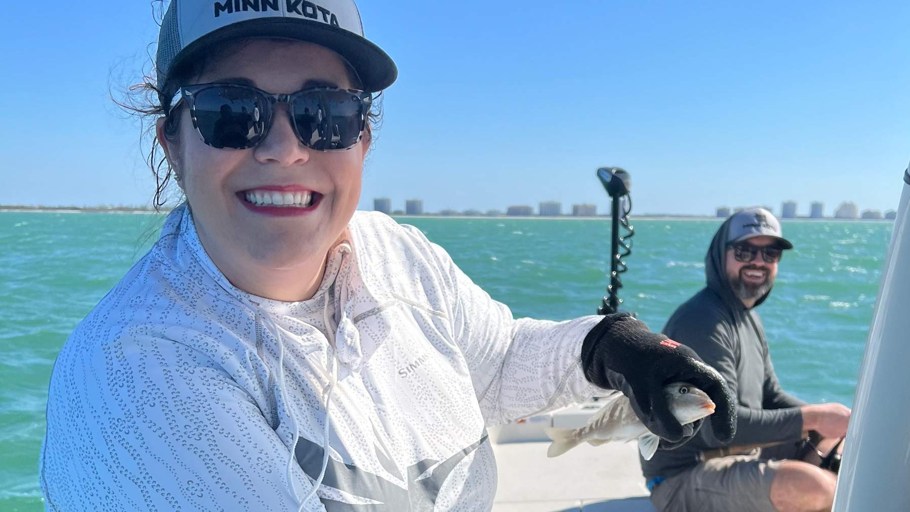 Woman on a boat holding a freshly caught fish.