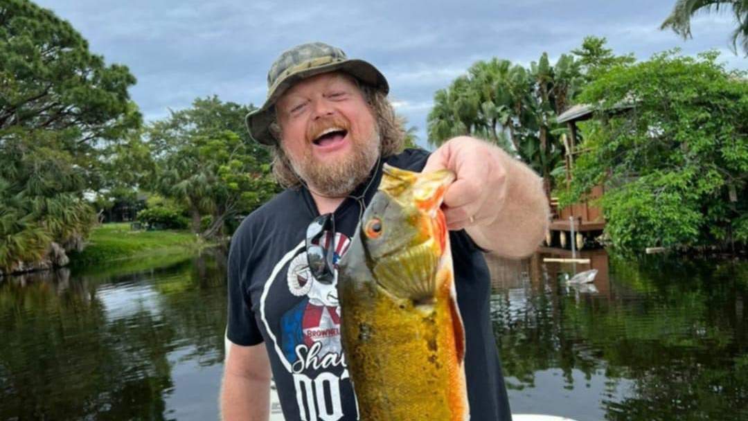 Man on a boat holding a freshly caught fish.