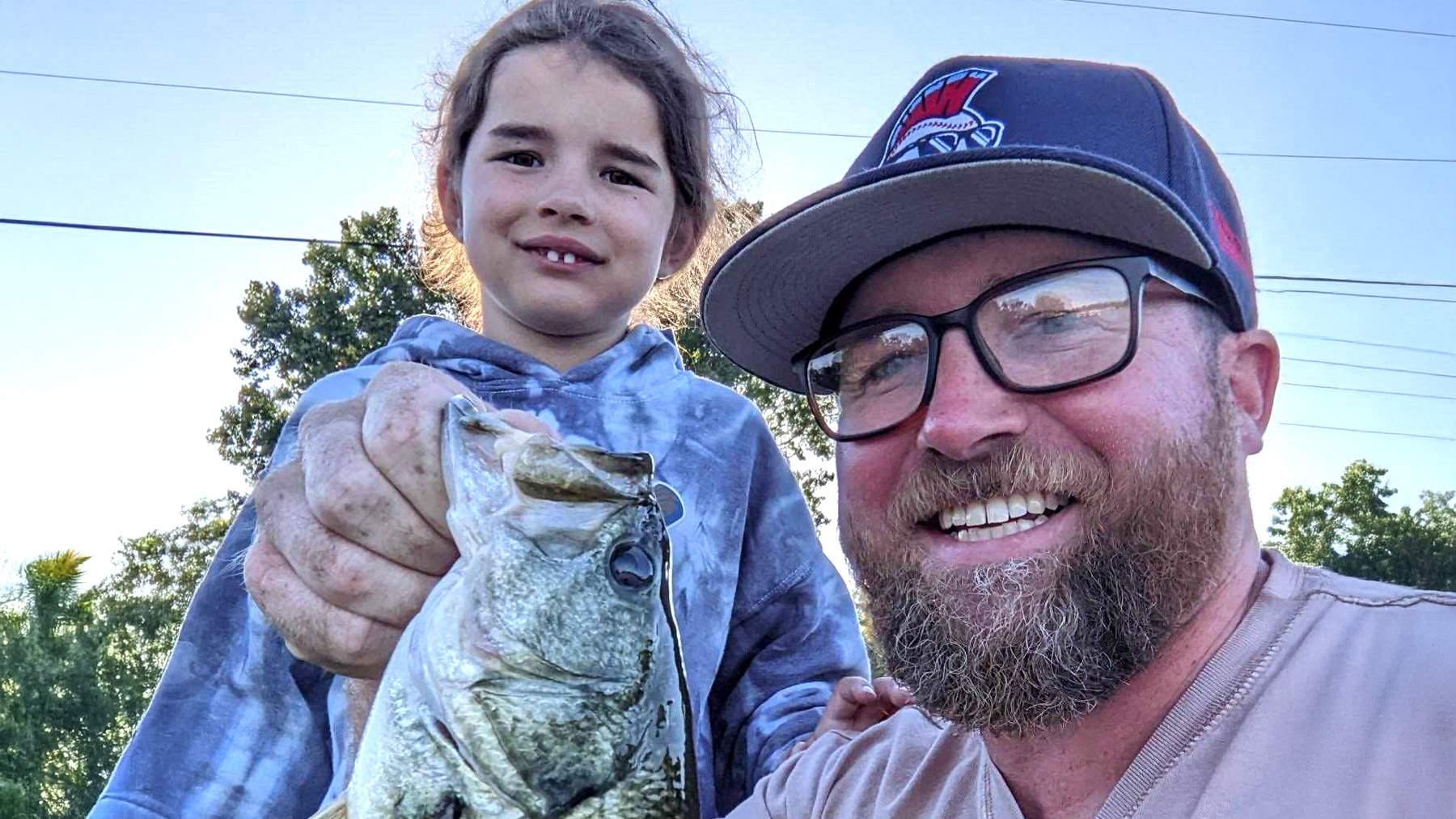 Man with child holding freshly caught fish.