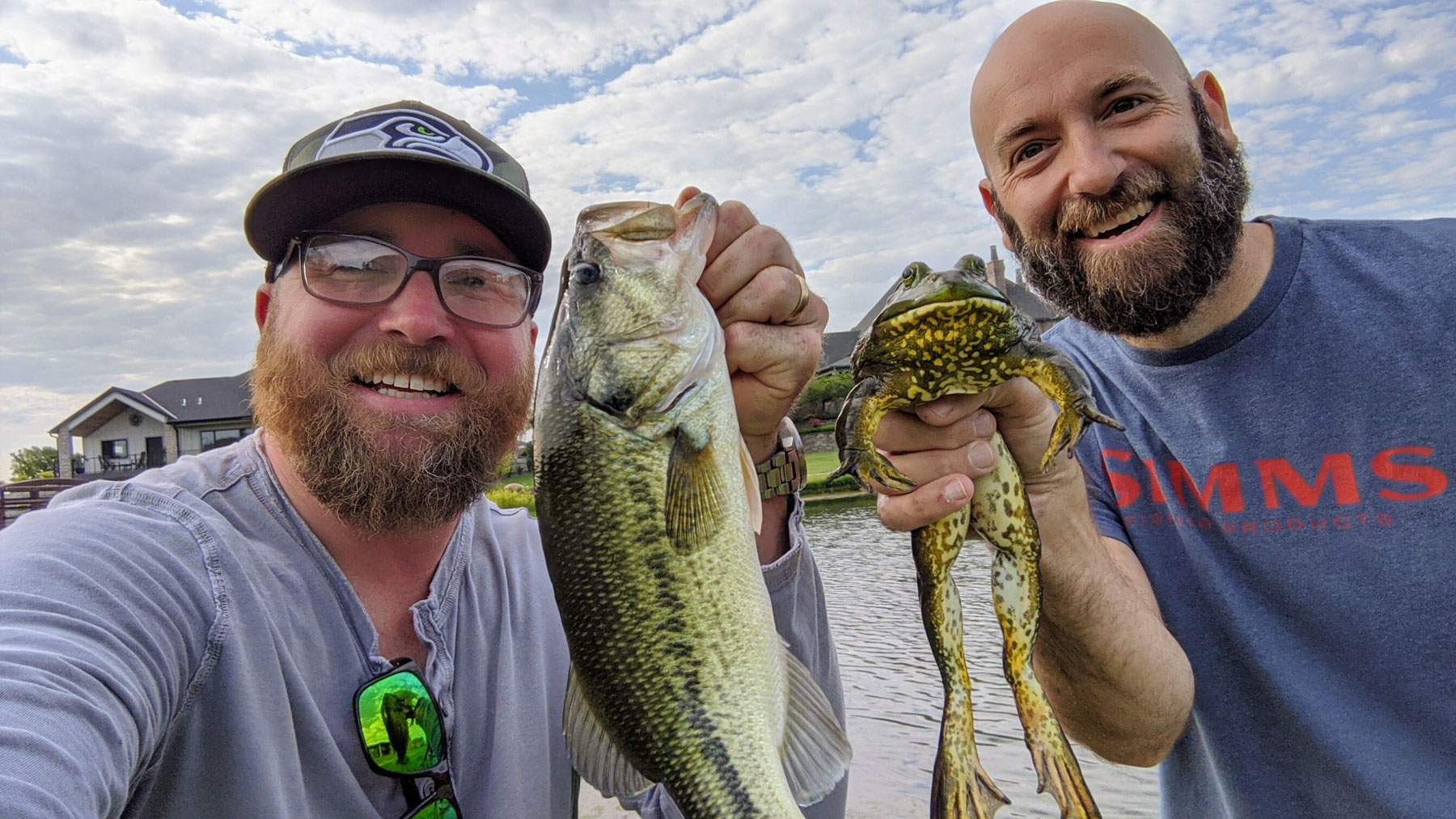 Two men on a boat holding freshly caught fish.
