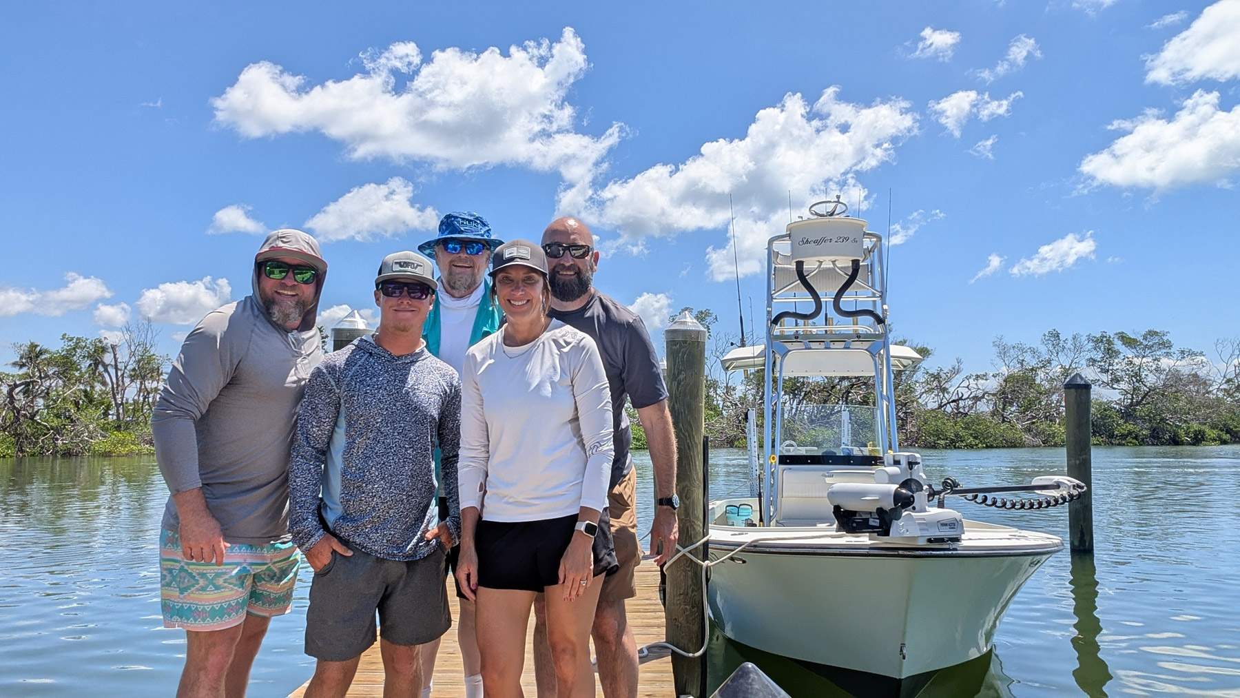 Team of people in front of a boat during fishing photoshoot.